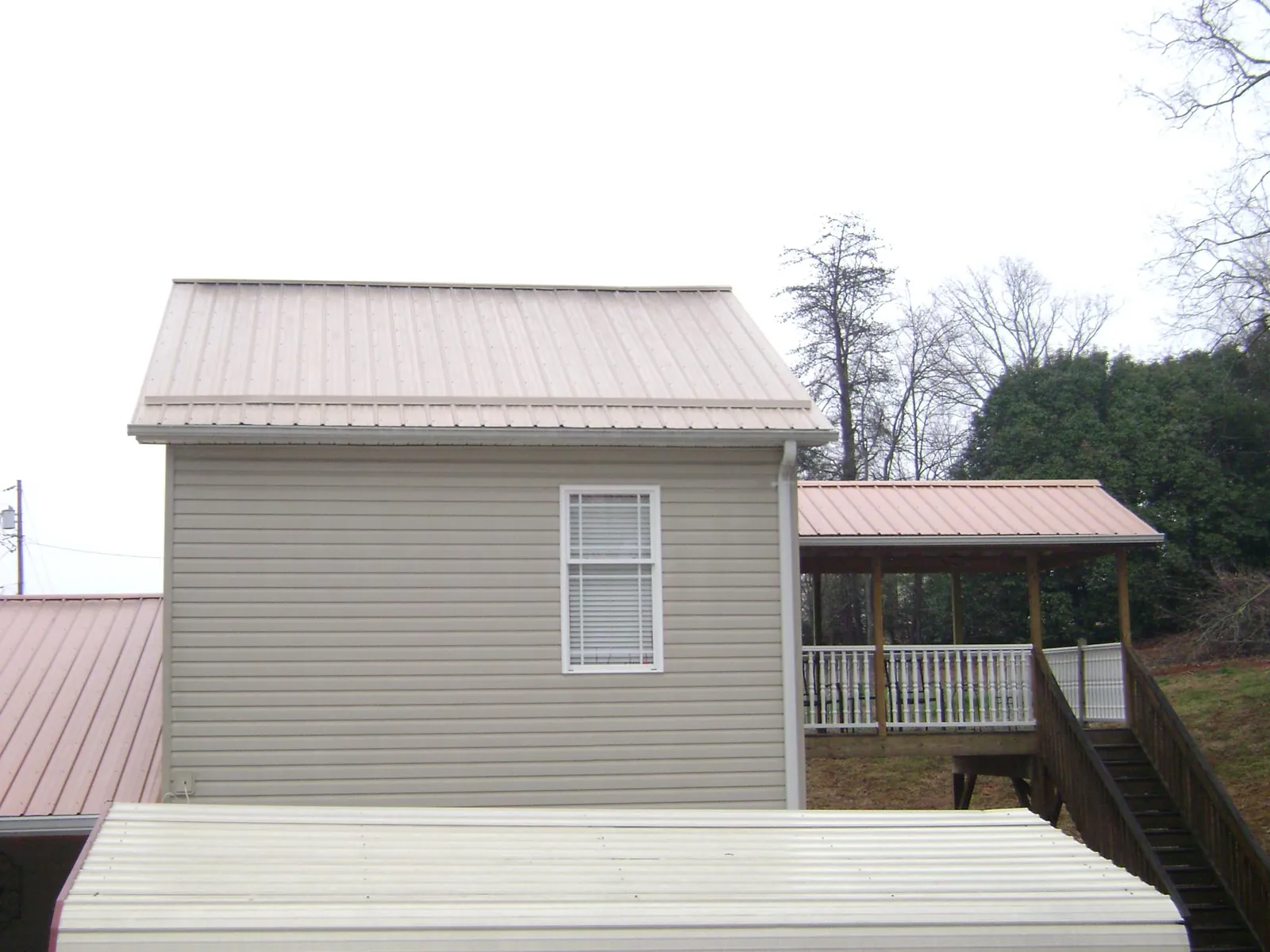 Tan metal roofs on a two story addition and attached porch, from a Roof Replacement job in Centreville